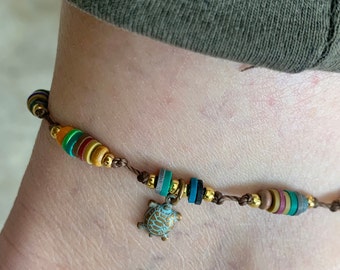 Turtle Anklet. Wood beads tiny gold and glass color beads.Brown cord that is Hand and Knotted and macrame. Adjusts to any size. Waterproof.