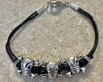 Pirates Bracelet. Black leather with Silver plate pirate beads. Hand knotted with silver lobster clasp. Bracelet measures 7” with a 1”chain.