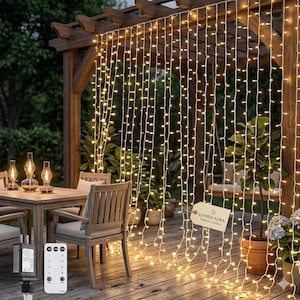 Peut inclure: Scène de patio extérieur avec des guirlandes lumineuses blanc chaud suspendues à une pergola en bois. Les lumières créent un effet de rideau, illuminant l'espace. Une table, des chaises et des plantes en pot sont visibles.