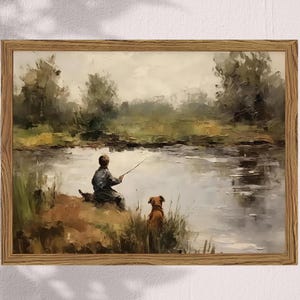 May include: A framed oil painting depicts a serene lakeside scene. A person is fishing, accompanied by a dog. The artwork features muted greens, browns, and blues, with a wooden frame.