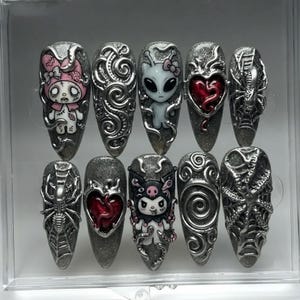 May include: A set of ten almond-shaped press-on nails with a silver glitter base. Designs include a zombie character, a grey alien, a red heart with veins, a spider on a web, and silver swirling 3D metallic accents on a dark grey background.