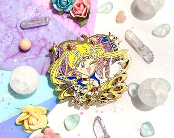 May include: Gold-tone enamel pin featuring a cartoon anime character with blonde hair, a blue and white sailor uniform, and a star on her chest. The character is surrounded by stars and a galaxy background.