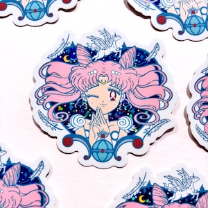 Könnte beinhalten: Ein Aufkleber mit einem zwinkernden Anime-Charakter mit rosa Haaren und einem roten Auge. Der Charakter ist von einem blau-weißen dekorativen Rand mit Sternen, Monden und einem Pegasus umgeben. Der Aufkleber hat einen glitzernden, holografischen Effekt.