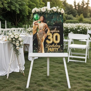以下が含まれることがあります： 白いイーゼルには、「Welcome to Sophia 30 Birthday Party」と書かれたパーティーサインが飾られています。サインには、金のドレスを着た女性、金の風船、緑と金の背景が描かれています。イーゼルは白い花で飾られています。