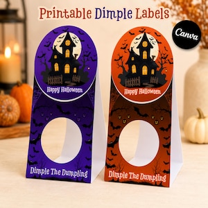 Può includere: Due etichette dimple stampabili a tema Halloween con una casa stregata, pipistrelli e una luna piena. Un'etichetta è viola e l'altra arancione. Entrambe riportano il testo Happy Halloween e Dimple The Dumpling con un foro circolare.
