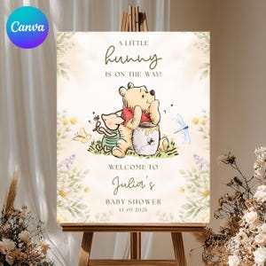 May include: A baby shower welcome sign featuring Winnie the Pooh and Piglet. The sign includes the text "A LITTLE hunny IS ON THE WAY!" and "WELCOME TO Julia's BABY SHOWER 15 05 2026". The design has a soft, watercolor style with floral accents.