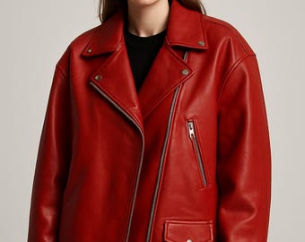 Könnte beinhalten: Eine leuchtend rote Lederjacke im klassischen Biker-Stil. Sie hat einen asymmetrischen Reißverschluss, einen Reverskragen und eine kleine Tasche mit Druckknopf. Die Jacke hat einen Taillengürtel und silberfarbene Hardware.