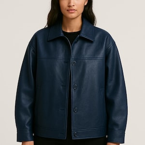 Puede incluir: Chaqueta azul marino con cuello y cierre de botones. La chaqueta tiene un corte cuadrado y dos bolsillos delanteros. El material parece ser polipiel lisa. La modelo lleva una camiseta negra.