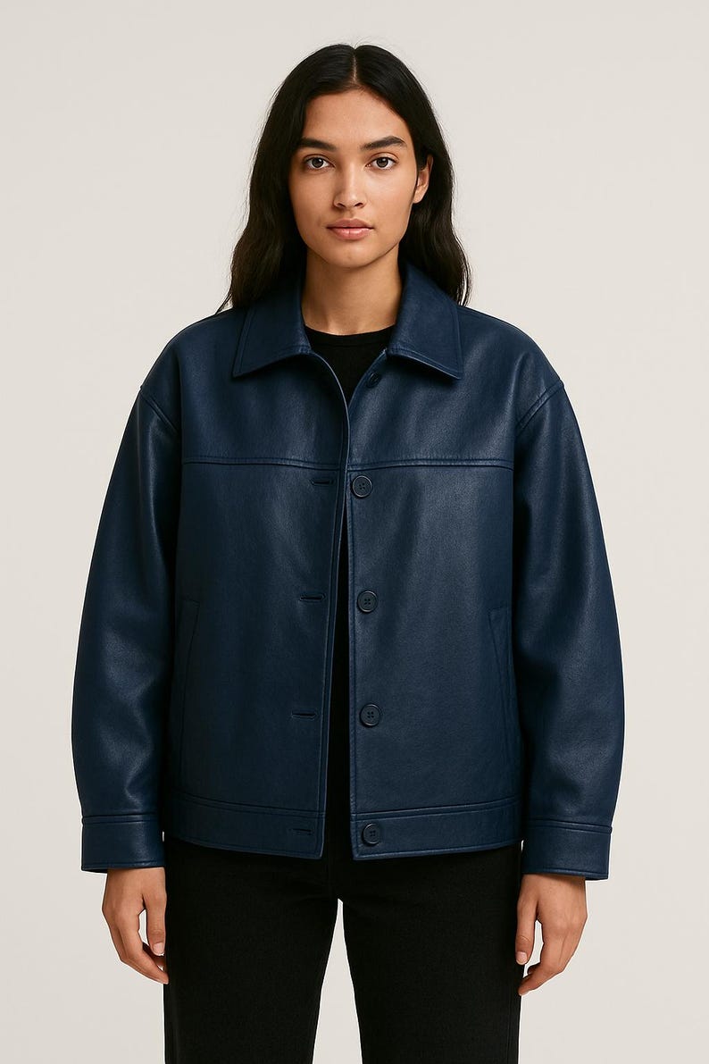 Puede incluir: Chaqueta azul marino con cuello y cierre de botones. La chaqueta tiene un corte cuadrado y dos bolsillos delanteros. El material parece ser polipiel lisa. La modelo lleva una camiseta negra.
