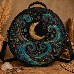 May include: A round black bag featuring a gold crescent moon at the center surrounded by swirling teal and blue wave patterns, gold star accents, and small teardrop shapes. The bag has a top handle and black side straps with metal hardware.