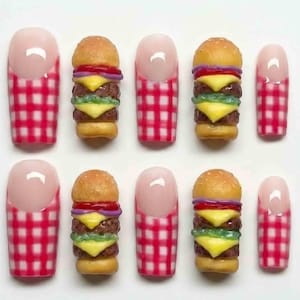 May include: A set of ten artificial nails. The nails alternate between a pink and red gingham pattern and miniature hamburger designs. The hamburgers have sesame seed buns, cheese, lettuce, tomato, and onion.