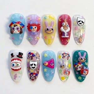 May include: A set of ten almond-shaped press-on nails featuring 3D character charms and colorful decals. Designs include a jester, a doll with button eyes, a purple rabbit, a chess piece, theater masks, teeth, and geometric shapes in various colors.