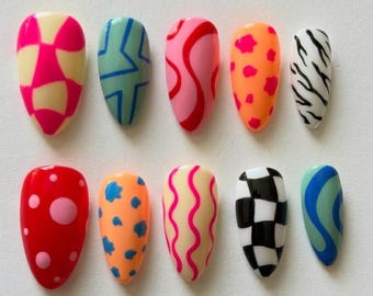 Puede incluir: Un conjunto de diez uñas postizas con varios diseños coloridos. Los diseños incluyen patrones geométricos, espirales y estampados de animales en tonos rosa, naranja, azul, negro y blanco. Las uñas son de forma ovalada.