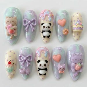 May include: A set of ten almond-shaped false nails with a pastel swirl design. Each nail features 3D embellishments, including a cat holding a strawberry, a panda, a bow, a heart, a paw print, and a cupcake.