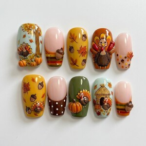 Könnte beinhalten: Ein Set aus zehn künstlichen Fingernägeln mit herbstlichen Motiven wie Truthähnen, Kürbissen, Eicheln und Ahornblättern. Die Nägel zeigen verschiedene Farben wie Orange, Gelb, Braun und Grün, einige mit erhabenen 3D-artigen Verzierungen.