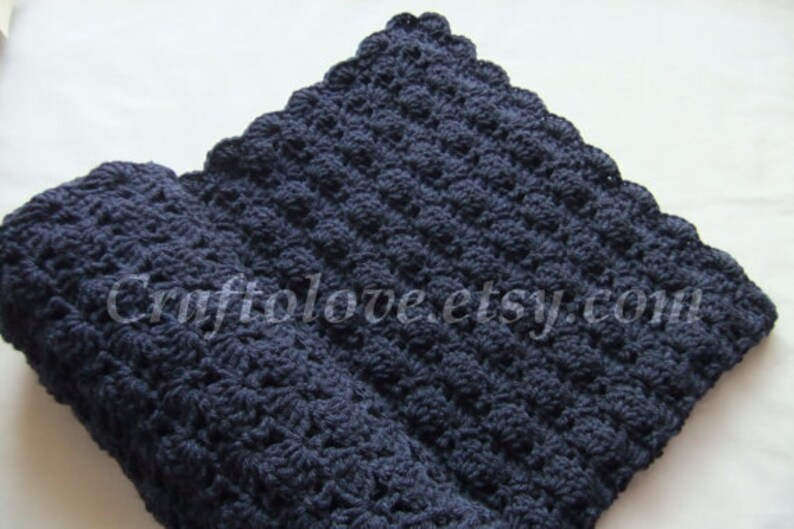 May include: A navy blue crocheted baby blanket with a scalloped edge.