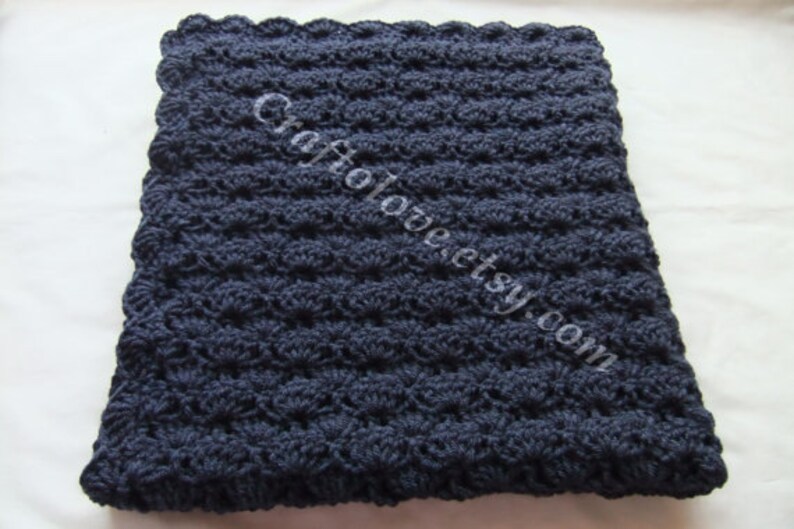 May include: A navy blue crocheted baby blanket with a scalloped edge.