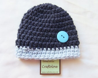 May include: A dark blue crocheted beanie with a light blue brim and a light blue button. The beanie has a tag that says "Handmade with love, Craftolove, www.craftolove.etsy.com".