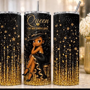 Op de afbeelding: Een zwarte en gouden glitterbeker met een rietje. De beker heeft een cartoonillustratie van een vrouw in een zwarte jurk en hoed, met de tekst "Queen of My Own Life". Gouden sterren en glitter versieren de beker.