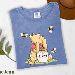 a blue t - shirt with a picture of a winnie the pooh holding a