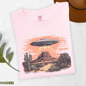 a pink shirt with an image of a flying saucer on it