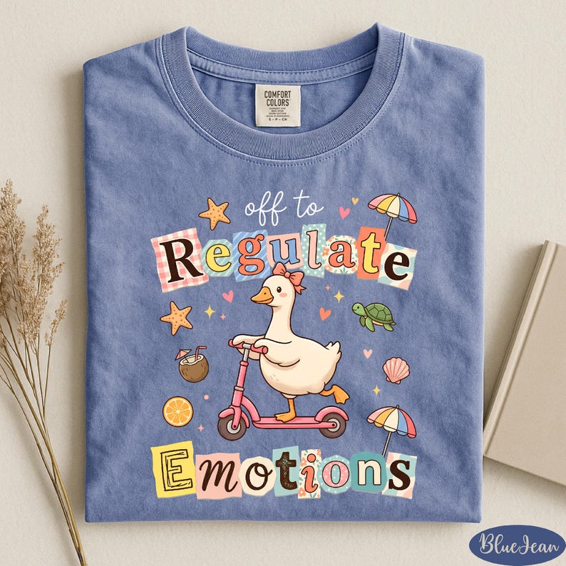 A blue t-shirt with a cartoon duck riding a pink scooter and the text "off to regulate emotions" printed on it.