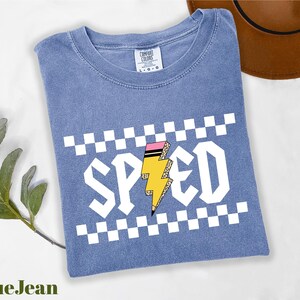 A blue t-shirt with a graphic design of a lightning bolt and the word "SPEED" printed on it, along with a brown hat and a green plant.