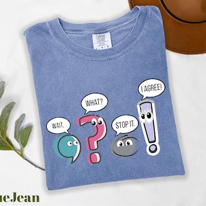 May include: Blue t-shirt with cartoon speech bubbles and characters. The speech bubbles say "Wait," "What?", "Stop it.", and "I Agree!". The text "BlueJean" is at the bottom left.