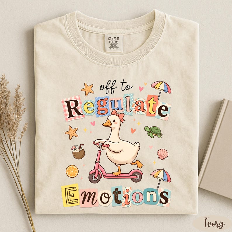 a t-shirt with a colorful and whimsical design, including a duck riding a scooter, surrounded by various objects such as umbrellas, flowers, and a book.