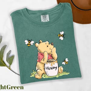 a t - shirt with a picture of a winnie the pooh holding a honey