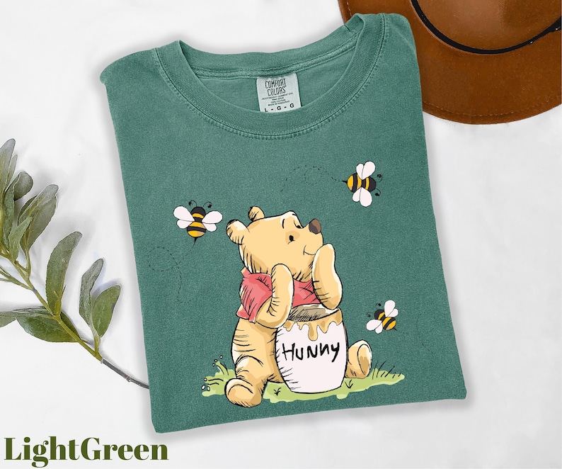 a t - shirt with a picture of a winnie the pooh holding a honey
