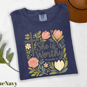 a t - shirt with the words she is worthy surrounded by flowers