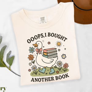 a white shirt with a duck holding a stack of books