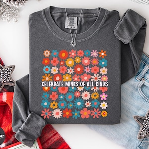 a gray long-sleeved shirt with a colorful floral design, a pair of blue jeans, and some decorative star-shaped embellishments.