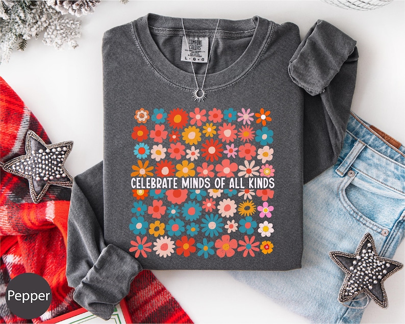 a gray long-sleeved shirt with a colorful floral design, a pair of blue jeans, and some decorative star-shaped embellishments.