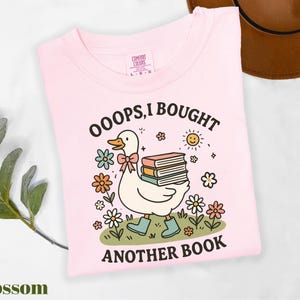 a pink shirt with a duck holding a stack of books