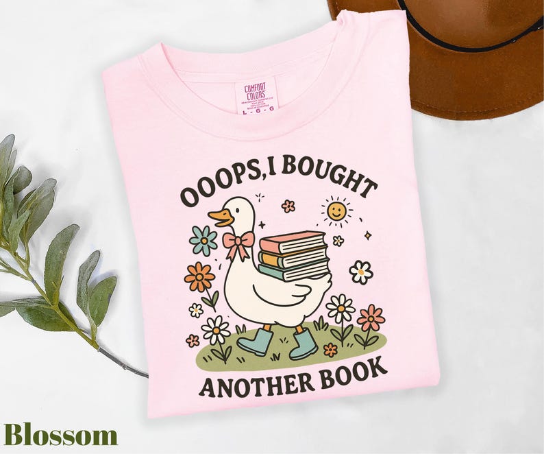 a pink shirt with a duck holding a stack of books