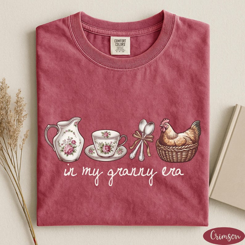 A red t-shirt with a printed design of a tea set and a chicken, accompanied by the text "in my granny era"