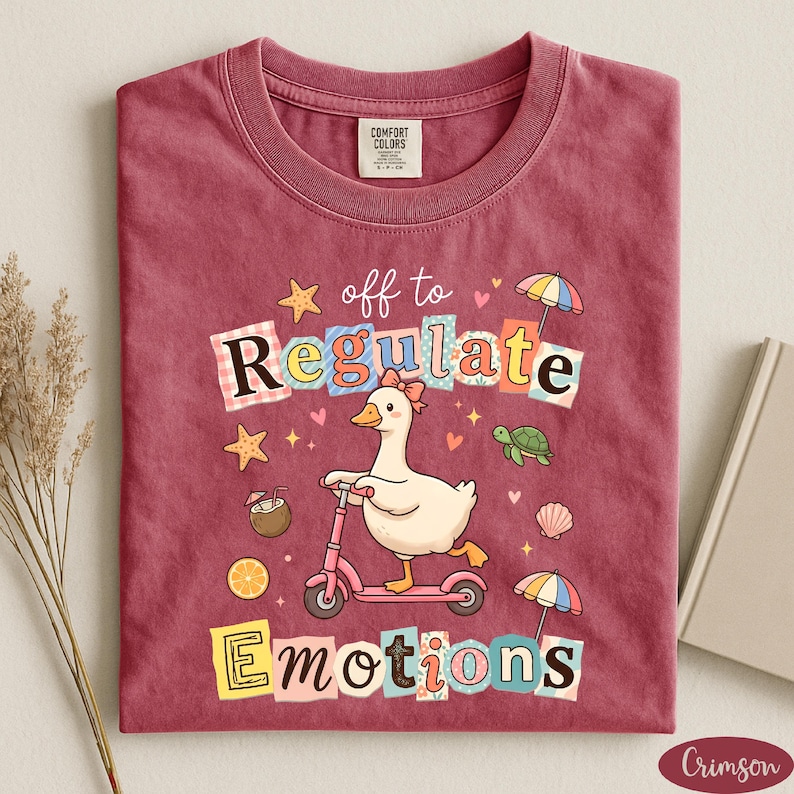 a red t-shirt with a cartoon duck riding a pink scooter, surrounded by various colorful objects such as umbrellas, flowers, and a book.