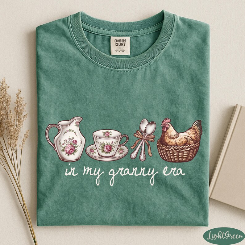 A green t-shirt with a printed design of a tea set and a chicken, accompanied by the text "in my granny era"