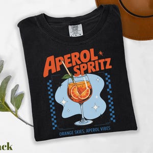 a black t - shirt with an orange drink on it