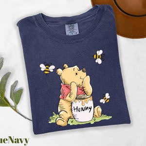 a t - shirt with a picture of a winnie the pooh holding a honey