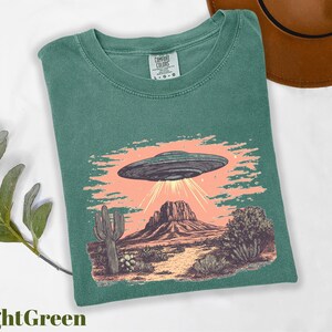 a green shirt with an image of a flying saucer