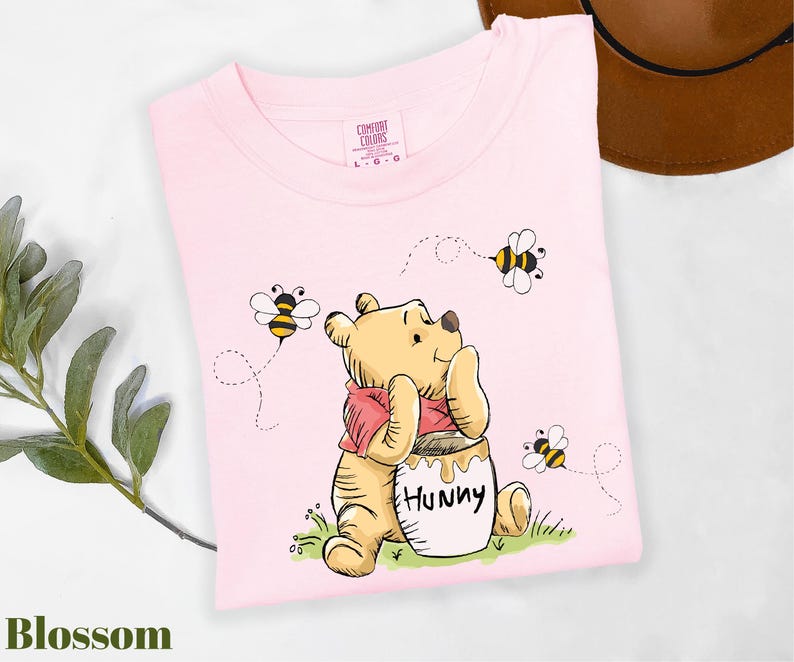 a pink t - shirt with a picture of a winnie the pooh holding a