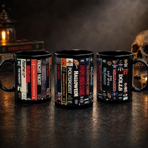 Peut inclure: Trois mugs noirs en céramique avec un motif enveloppant représentant des dos de cassettes VHS de films d'horreur classiques. Les titres incluent "Vendredi 13", "Halloween" et "Hellraiser". Chaque mug a une anse noire.