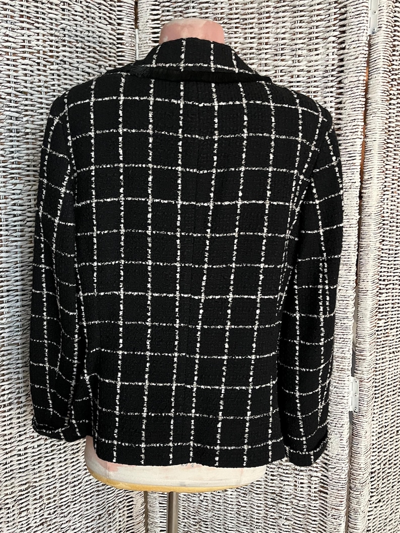 K&ouml;nnte beinhalten: Schwarz-wei&szlig; kariertes Blazer mit Kragen. Der Blazer ist aus einem tweedartigen Stoff.