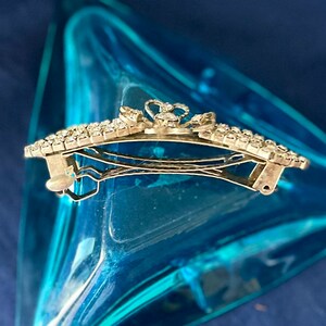May include: A silver hair clip with a crown design and clear rhinestones. The clip is open and ready to be used.
