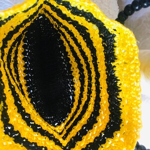 May include: A black and yellow crocheted bag with a black beaded handle.