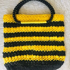 May include: A yellow and black striped crocheted tote bag with a black beaded handle.
