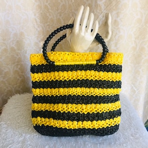 May include: A black and yellow striped crocheted tote bag with black bead handles.